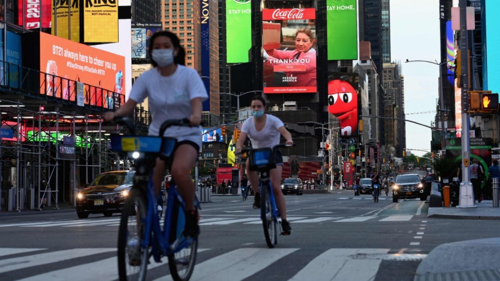 Dos chicas con mascarilla montando en bicicleta por Times Square, Nueva York.