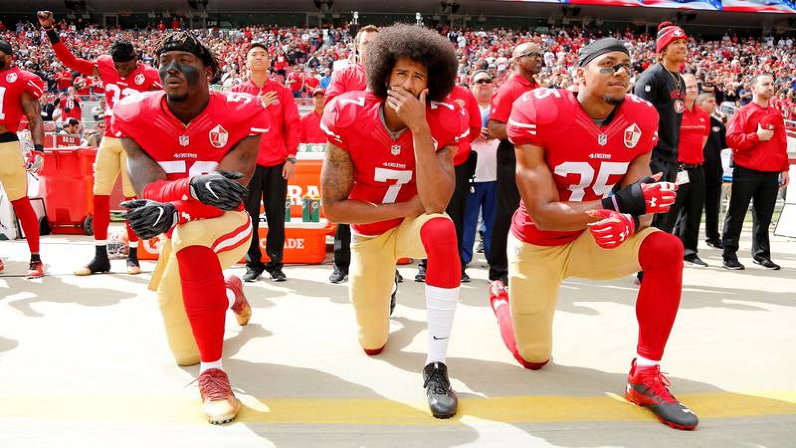Colin Kaepernick (centro), arrodillado junto a otros dos jugadores mientras sonaba el himno de EE.UU. antes de un partido de la NFL de 2016