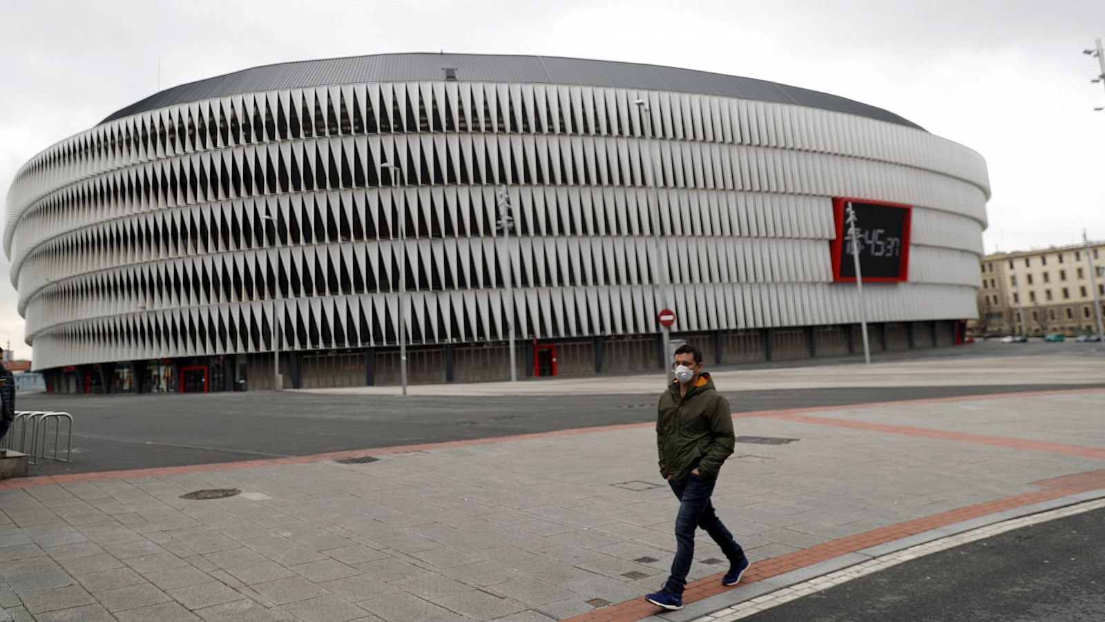 Un hombre con mascarilla pasa por delante del estadio de San Mamés