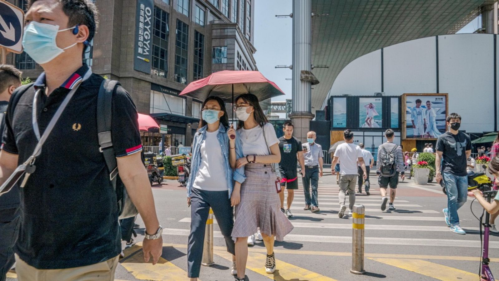 Viandantes con mascarilla cruzan la calle en el distrito comercial de Pekín, China, cuando el país ya ha conseguido controlar la pandemia de coronavirus.