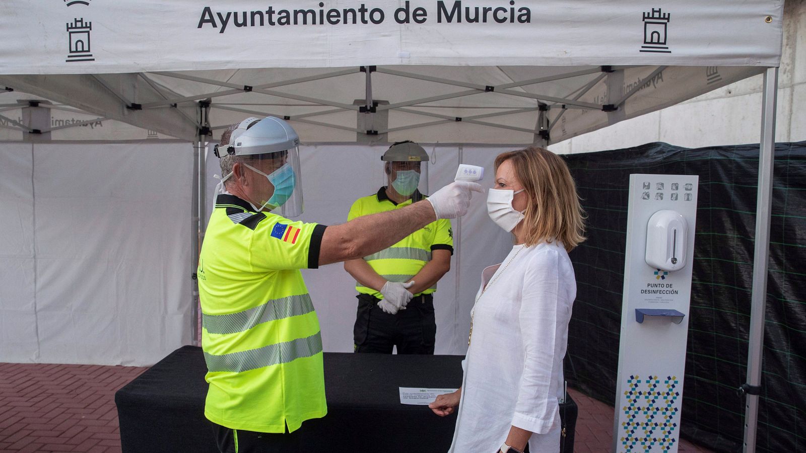 Un sanitario toma la temperatura a una mujer a la entrada al auditorio Murcia Parque