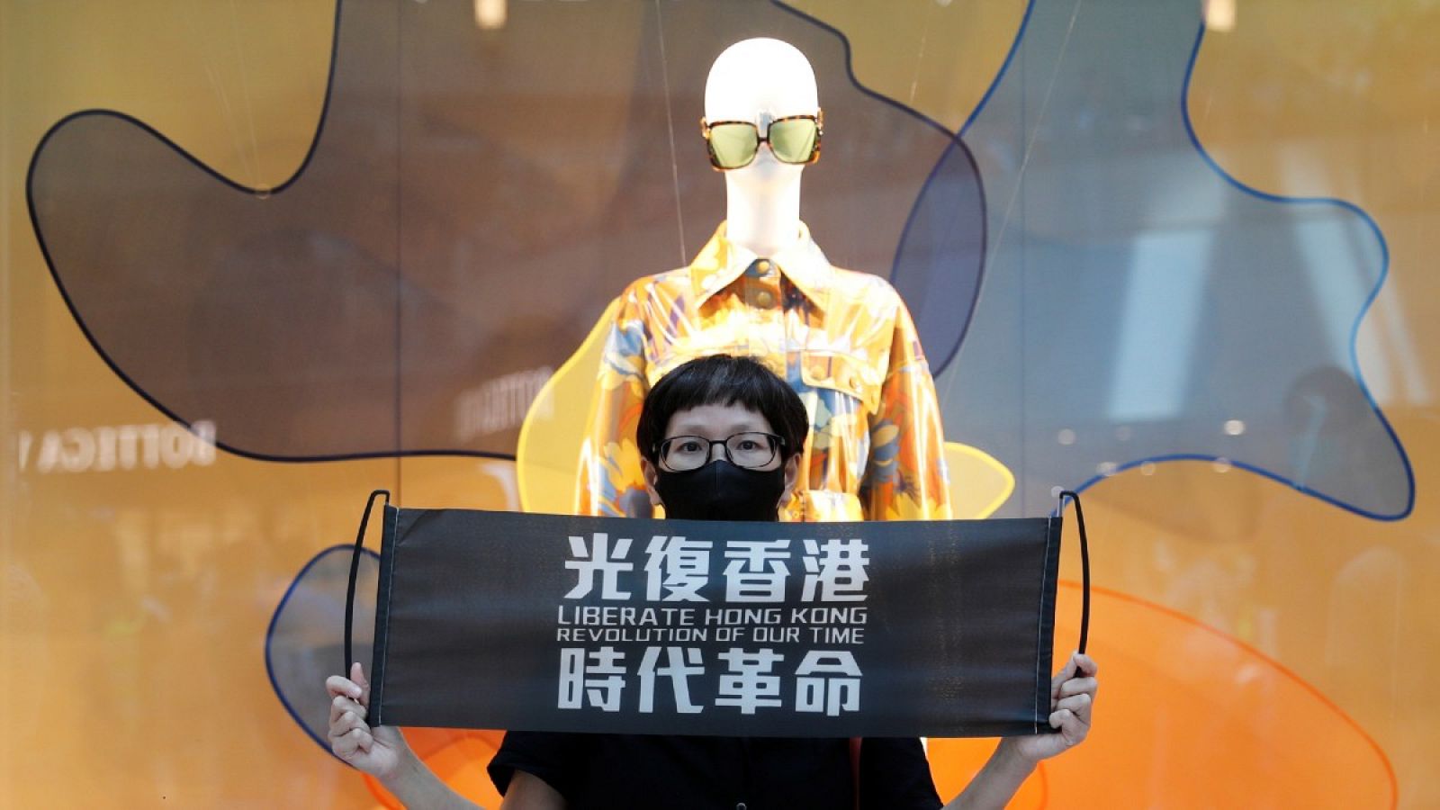 Un manifestante sostiene una pancarta con "Libera a Hong Kong, la Revolución de nuestro tiempo" en una protesta contra Pekín