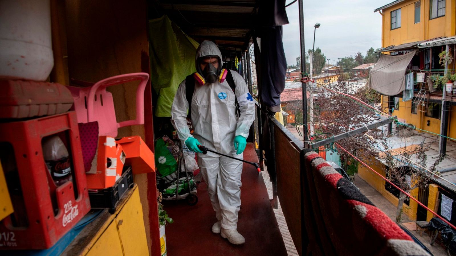 Un trabajador municipal limpia y desinfecta una barrio pobre en Santiago