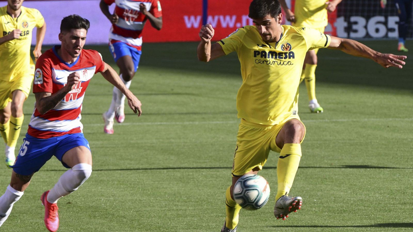 El delantero del Villarreal Gerard Moreno (d) controla el balón ante el defensa del Granada Carlos Neva