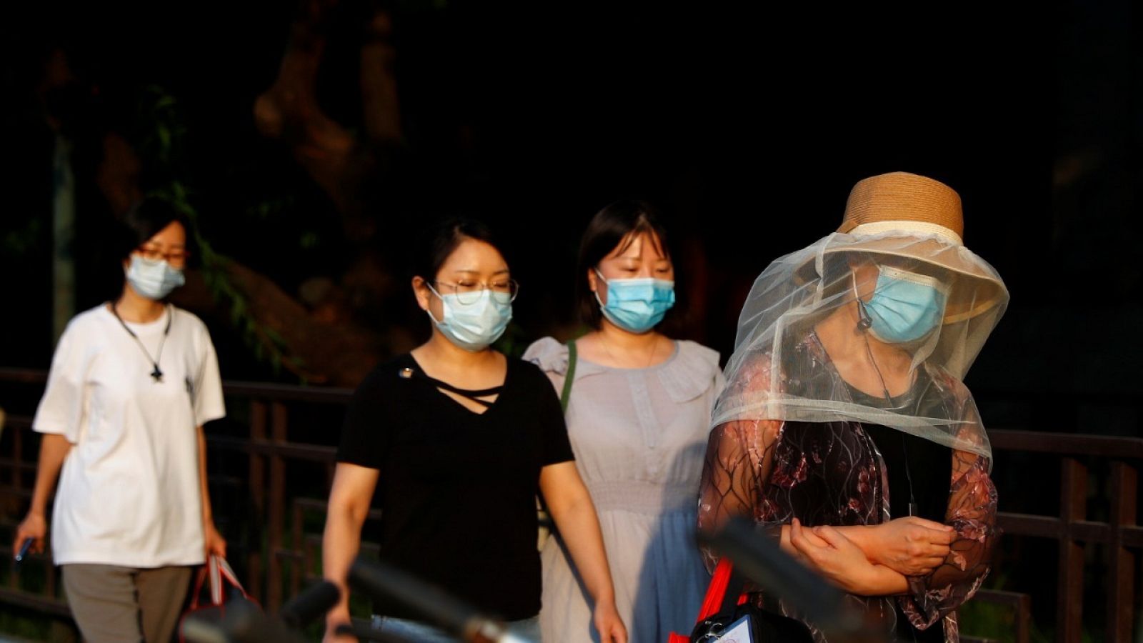 Cuatro mujeres con mascarilla caminando por una calle de Pekín.