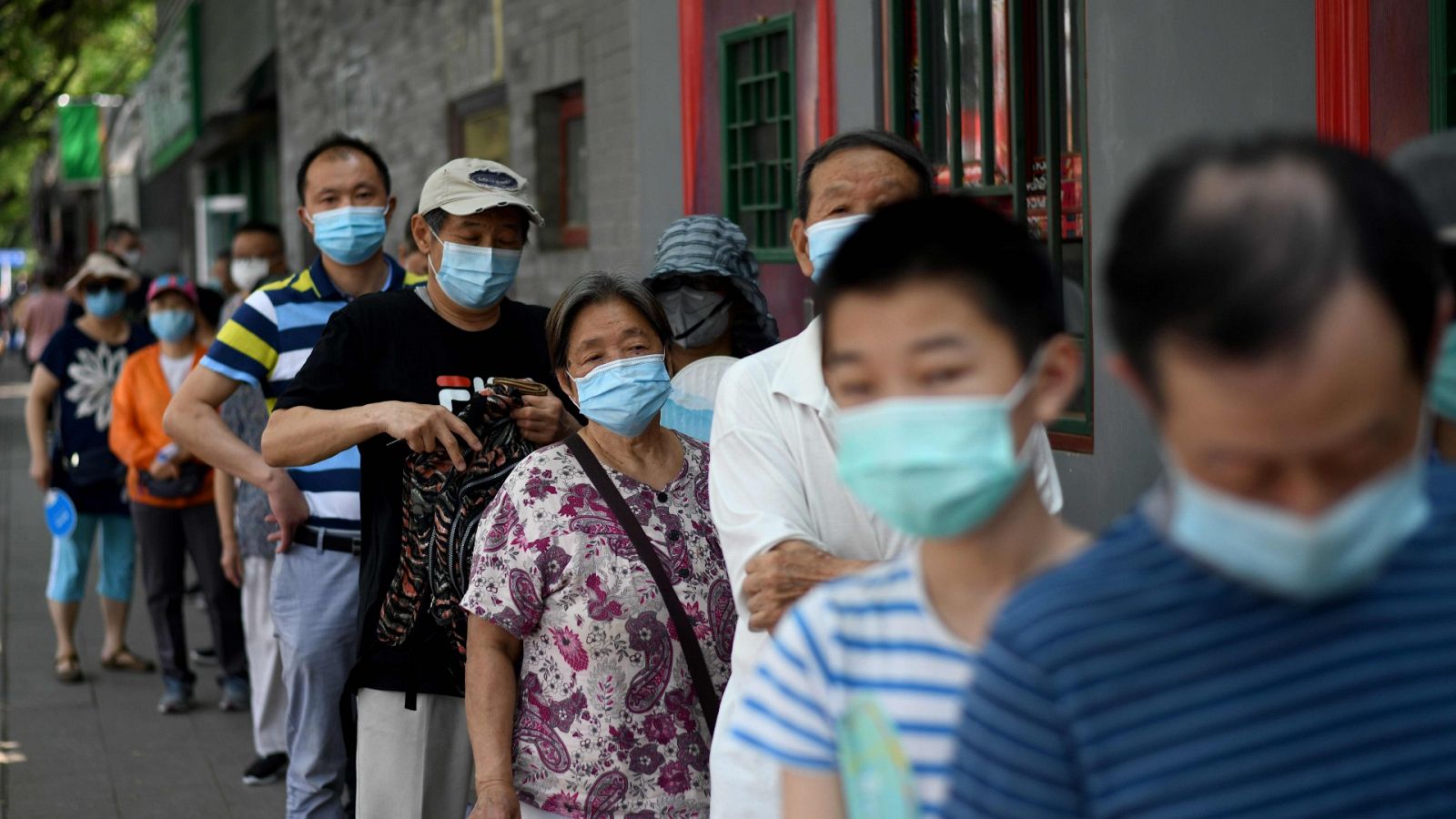 Ciudadanos chinos con mascarilla hacen cola para realizarse la prueba del coronavirus en Pekín