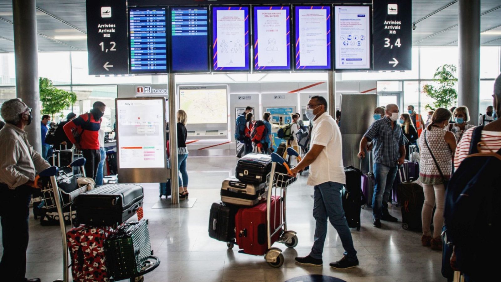 Pasajeros consultan el horario de sus vuelos en un aeropuerto