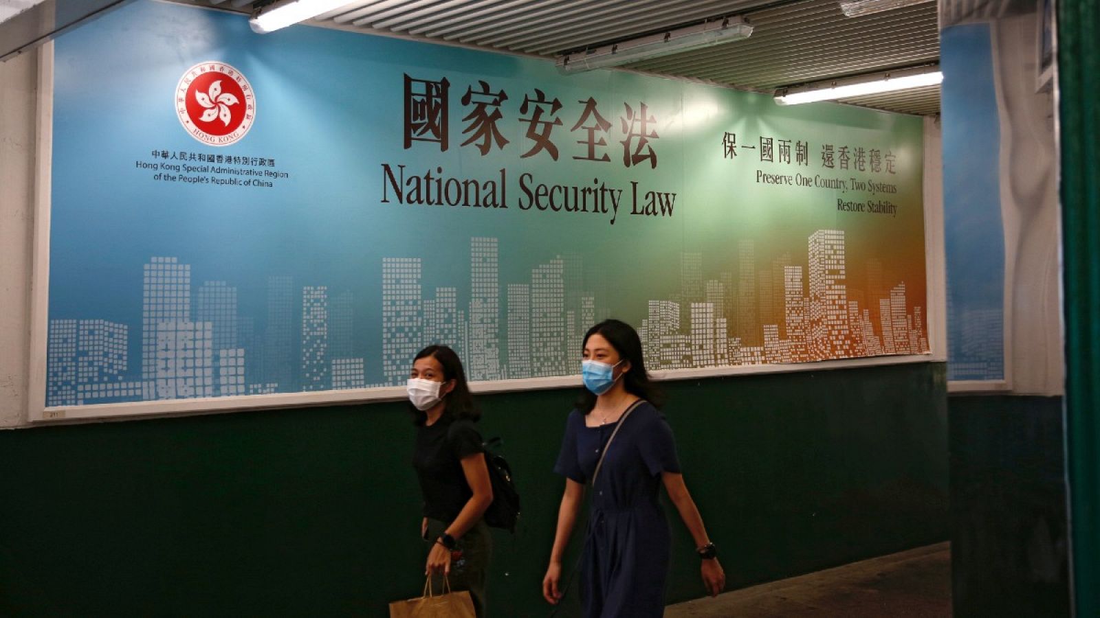 Mientras se debate la aprobación de la ley de seguridad nacional, dos mujeres pasan por delante de un anuncio del gobierno en defensa de su entrada en vigor en Hong Kong