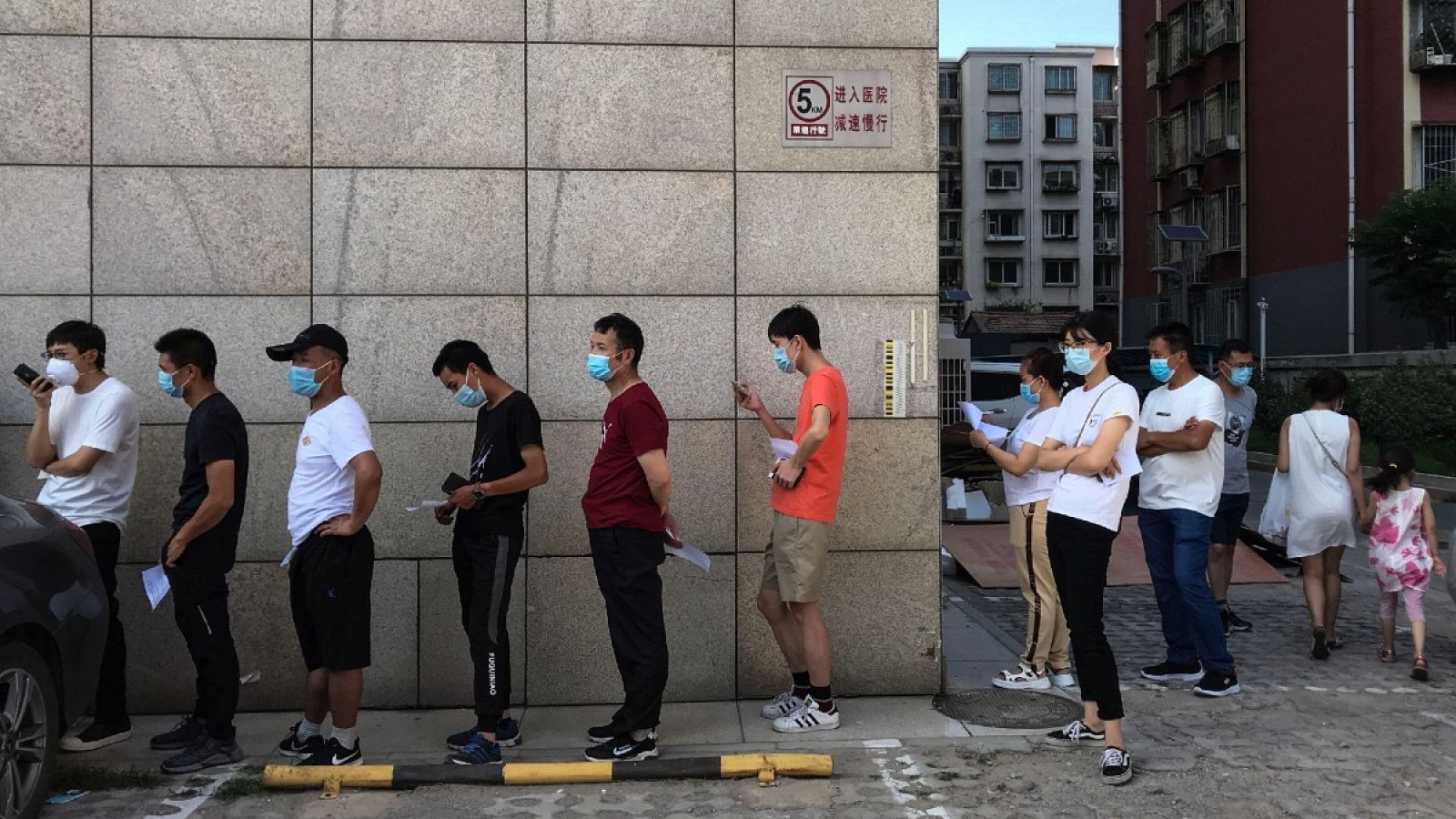 Un grupo de ciudadanos chinos hace cola para hacerse las pruebas del coronavirus tras el rebrote en Pekín