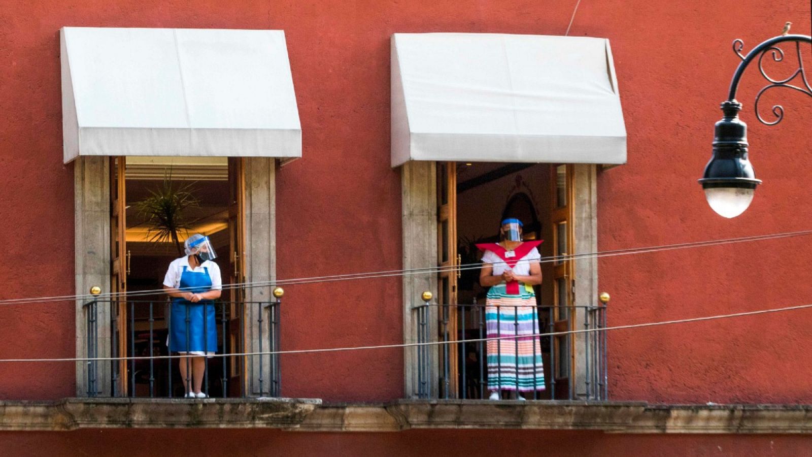 Dos trabajadoras con mascarilla en el balcón de un restaurante en Ciudad de México.