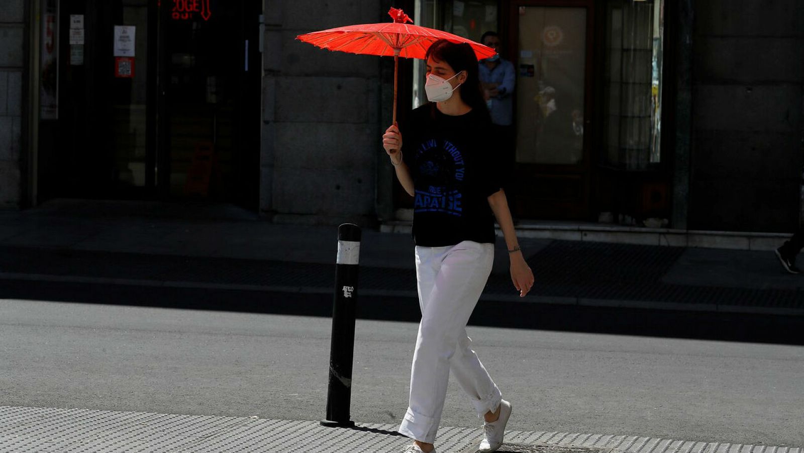 Una viandante se protege del sol con una sombrilla en el centro de Madrid.