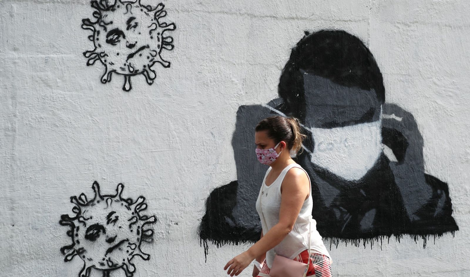 Una mujer camina frente a un mural del coronavirus en Río de Janeiro