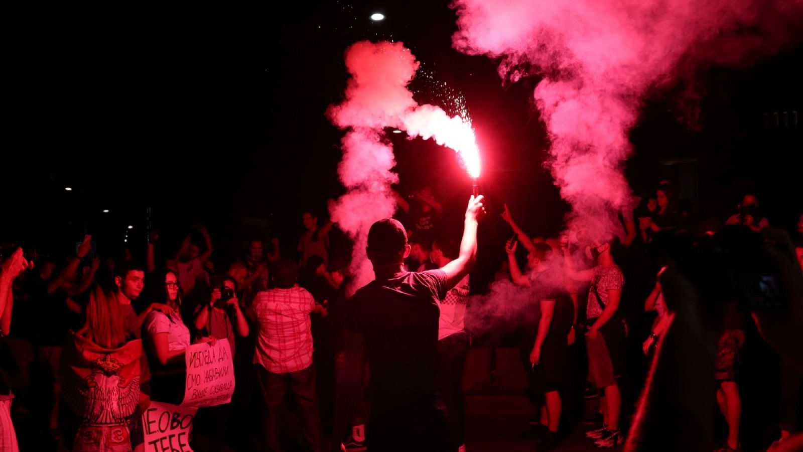 Un manifestante sostiene una bengala en las protestas contra el confinamiento de este jueves frente al parlamento serbio, en Belgrado