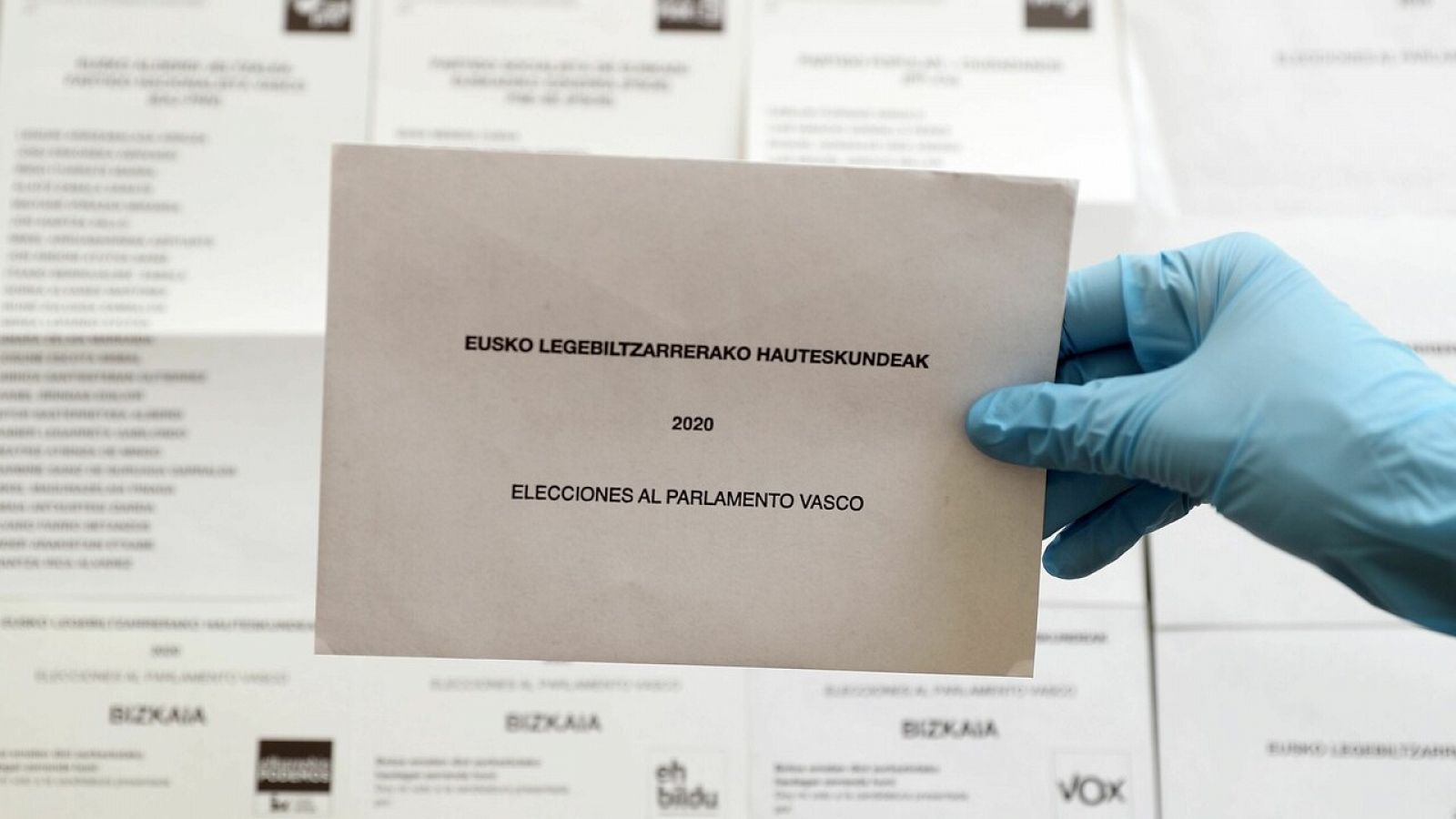 Un sobre para depositar el voto junto a diferentes opciones políticas al Parlamento Vasco, de cara al domingo 12 de julio