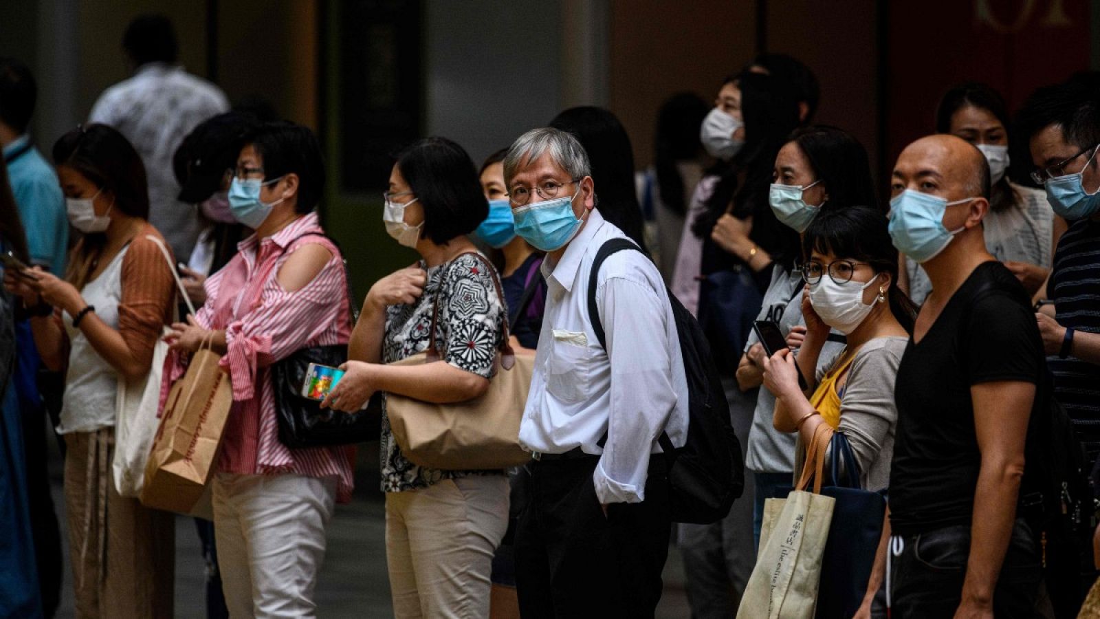 Un grupo de peatones con mascarillas espera para cruzar la calle en Hong Kong, donde se ha detectado un nuevo brote de contagios locales de coronavirus.