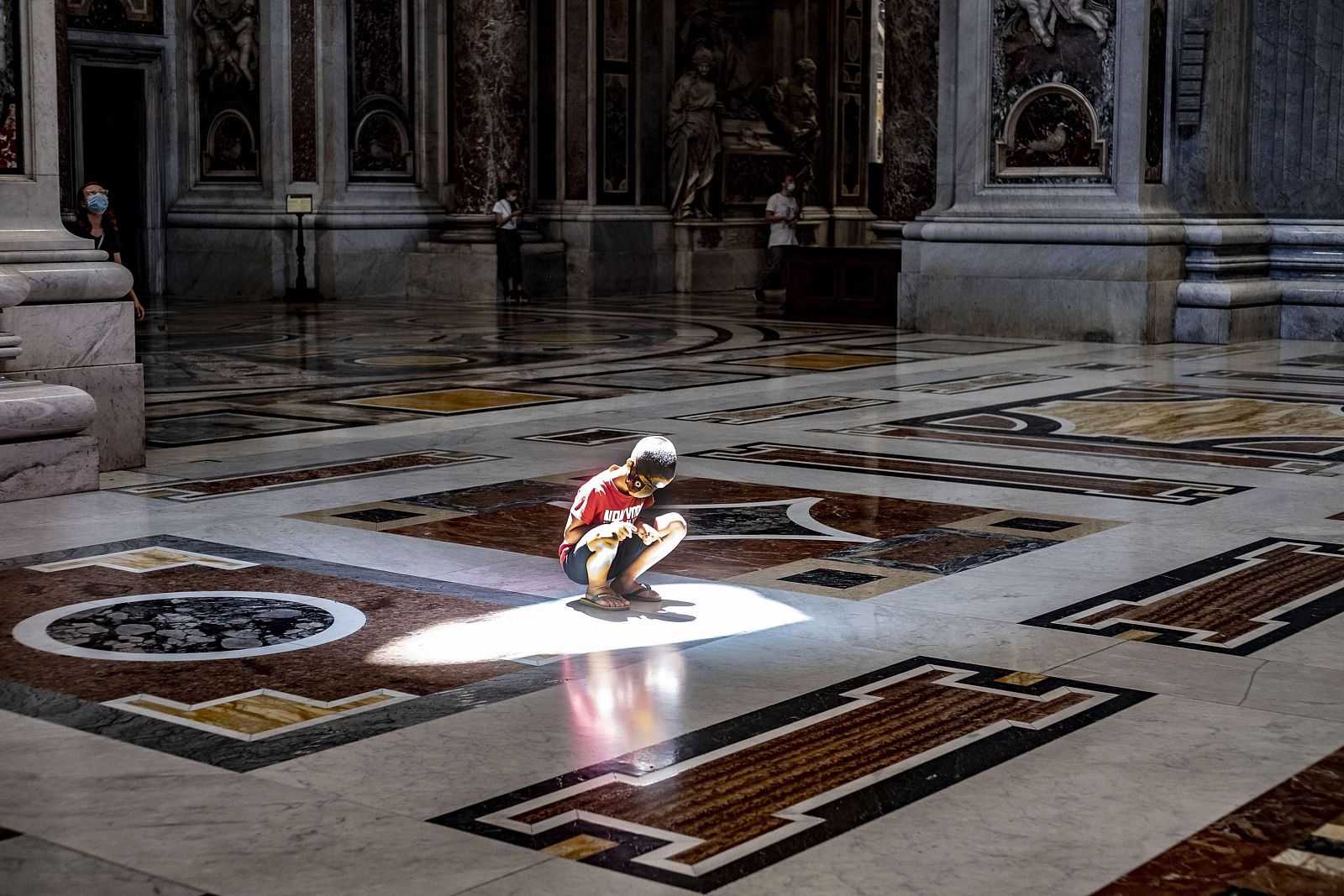 Un niño sentado en el suelo de la basílica de san Pedro, en el Vaticano, en plena ola de calor.