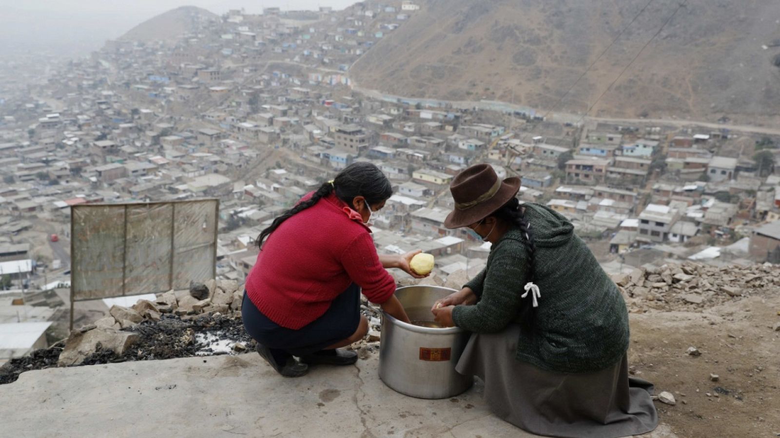 Dos mujeres con mascarilla pelando patatas en el  distrito de San Juan de Miraflores, Perú.