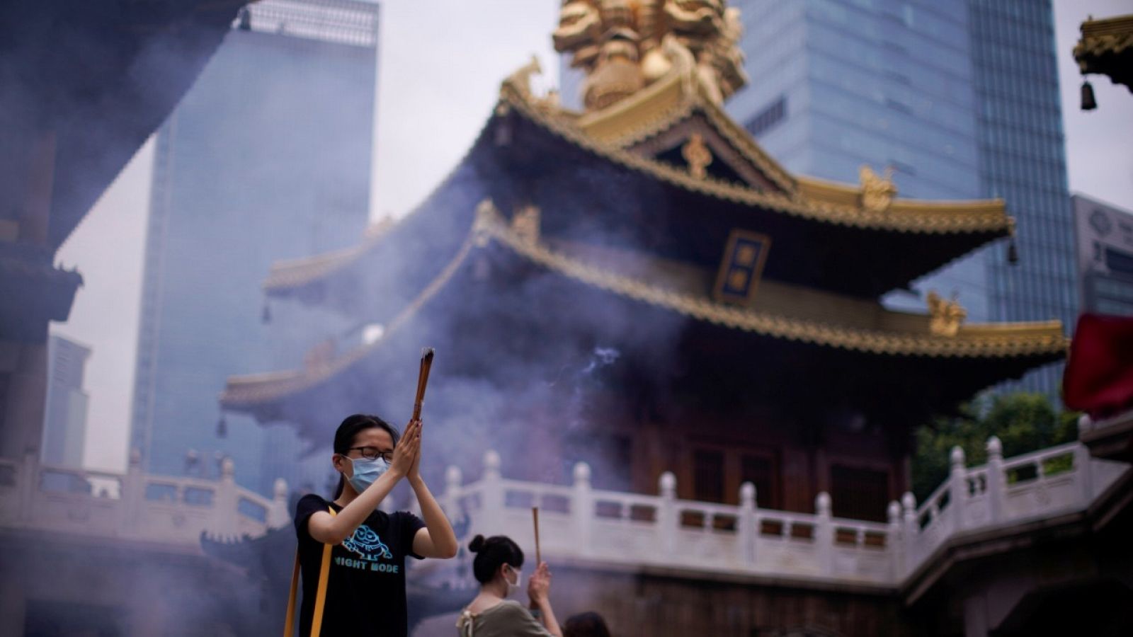 Varias personas con mascarilla rezando en un templo budista en Shanghái, China.