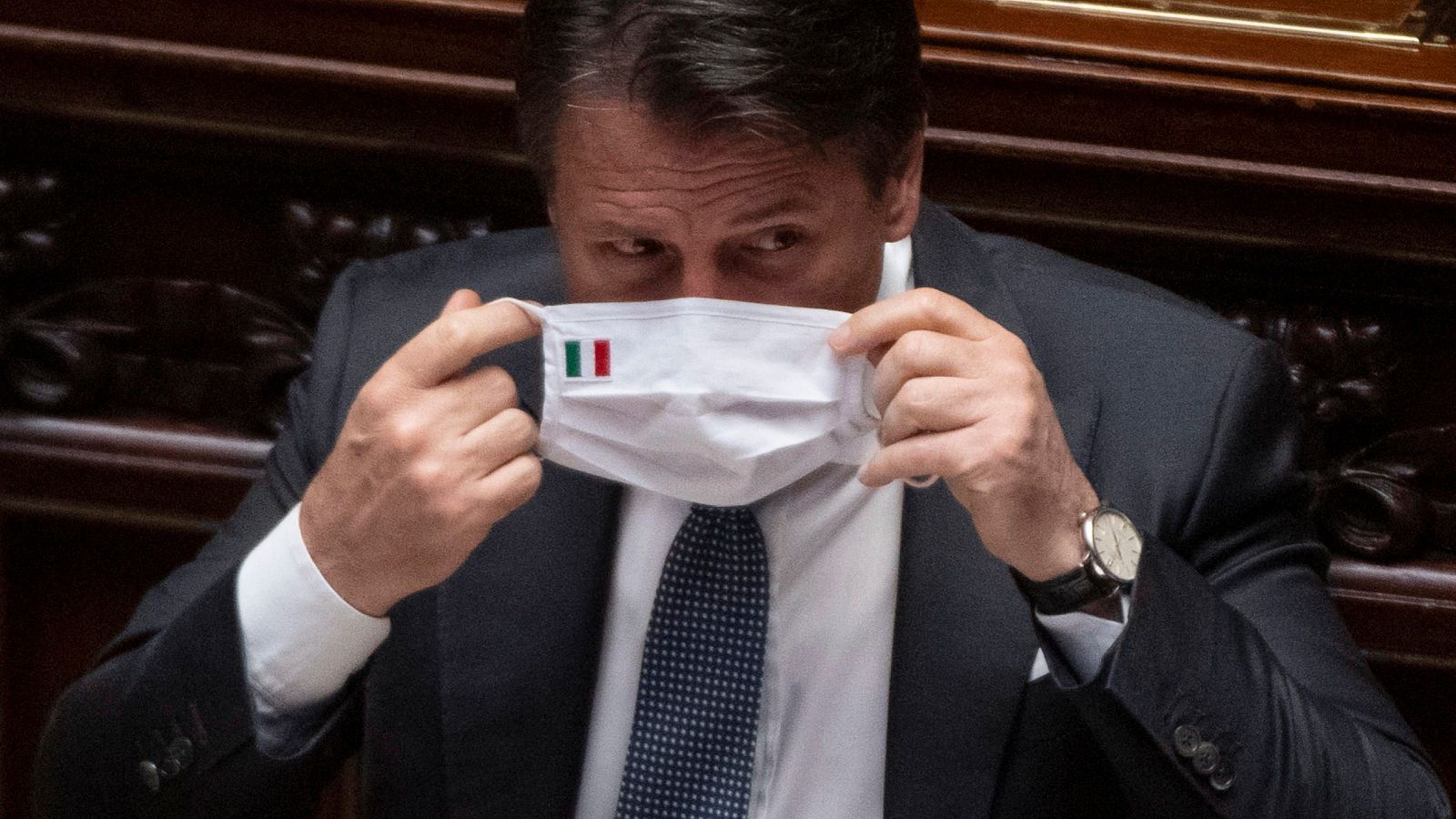Giuseppe Conte se coloca una mascarilla con la bandera de Italia.