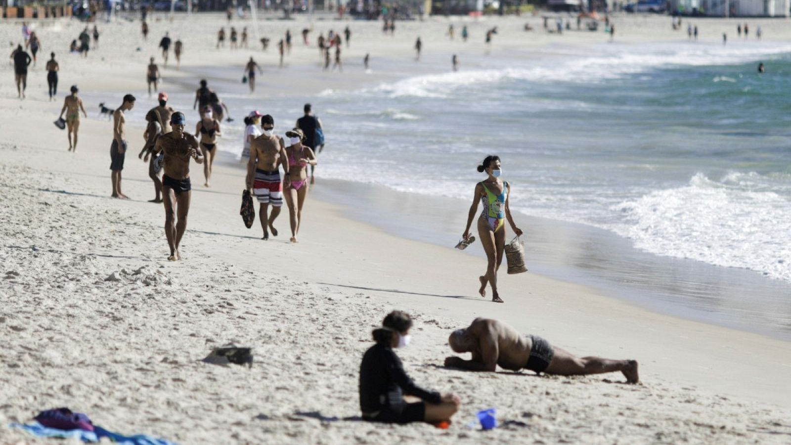 Algunos bañistas pasean por la playa de Copacabana con mascarillas durante el brote de coronavirus en Brasil, a finales de julio 