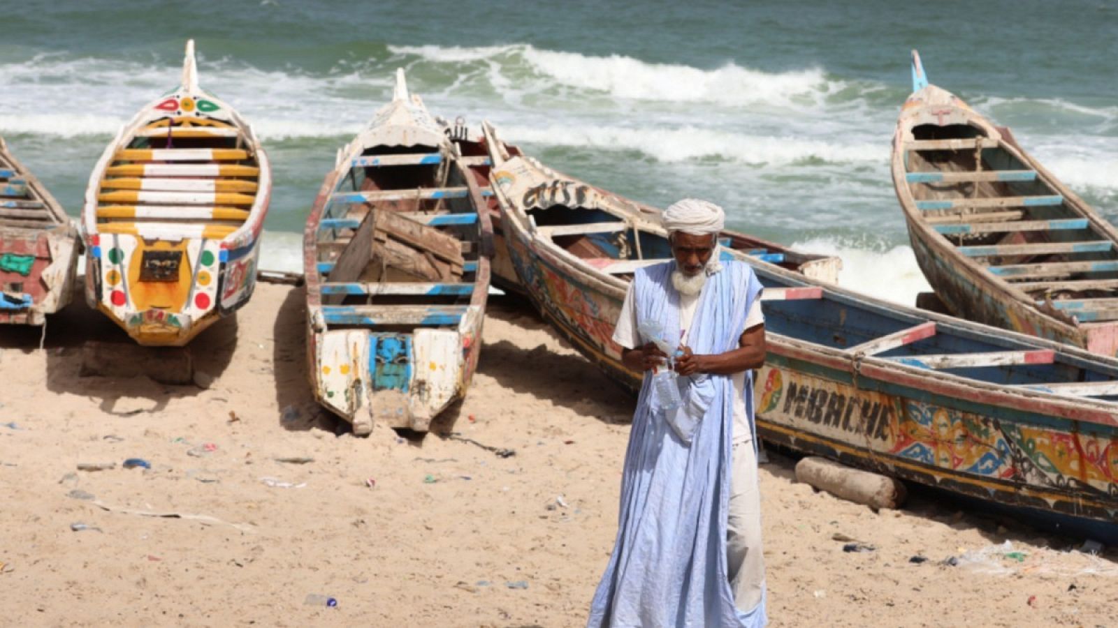 Imagen de archivo de un hombre frente a unos barcos de pesca en la costa de Nuadibú, Mauritania.