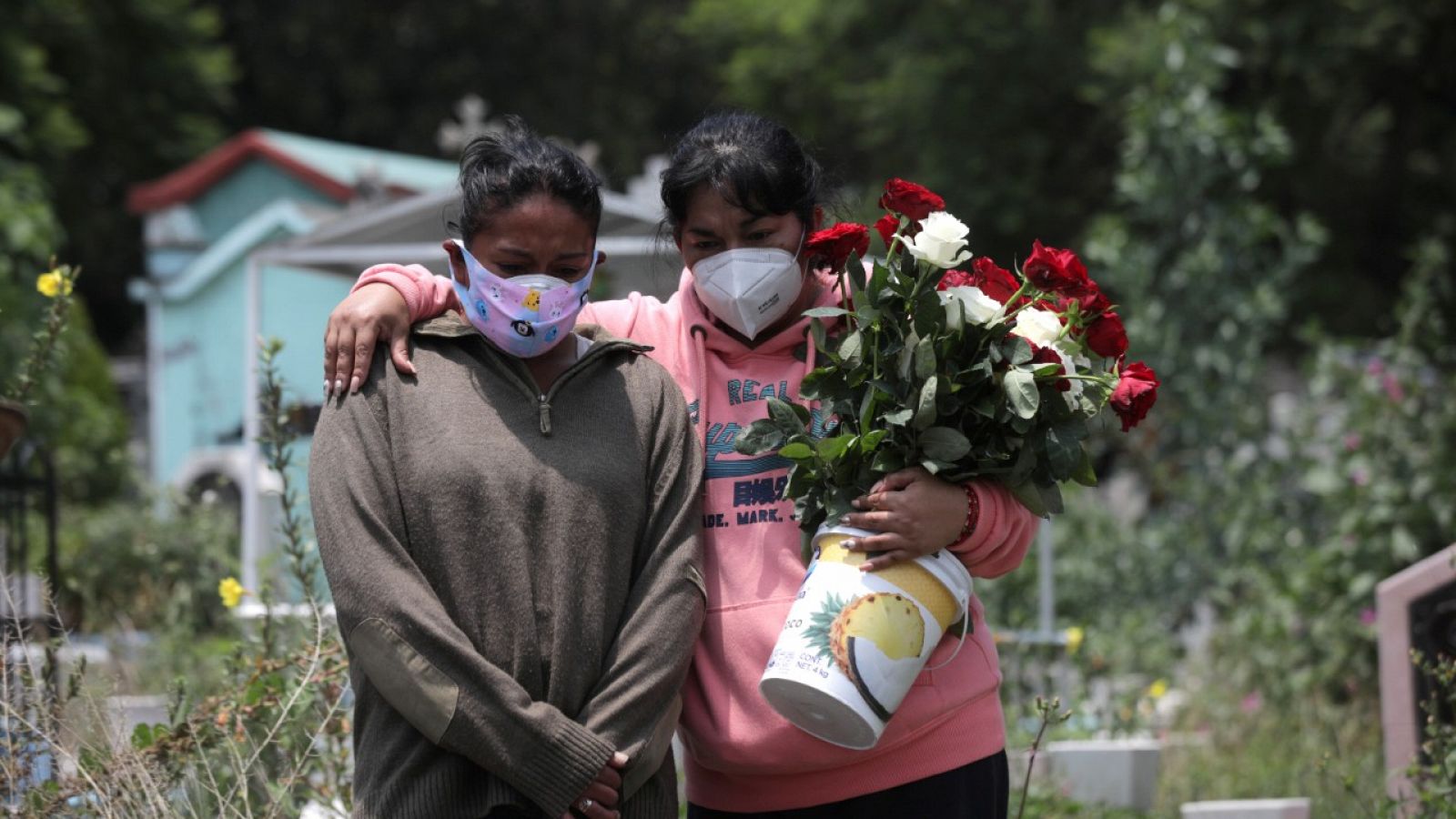 Dos mujeres con mascarilla durante el entierro de un familiar en un cementerio de Ciudad de México.