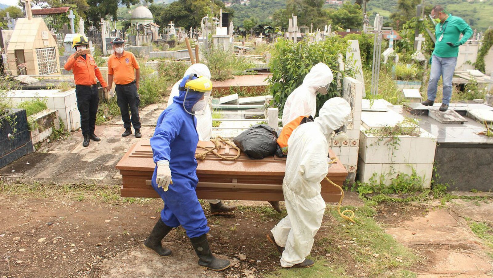Trabajadores gubernamentales proceden a enterrar un féretro con una víctima de COVID-19 en San Cristóbal, Venezuela. 