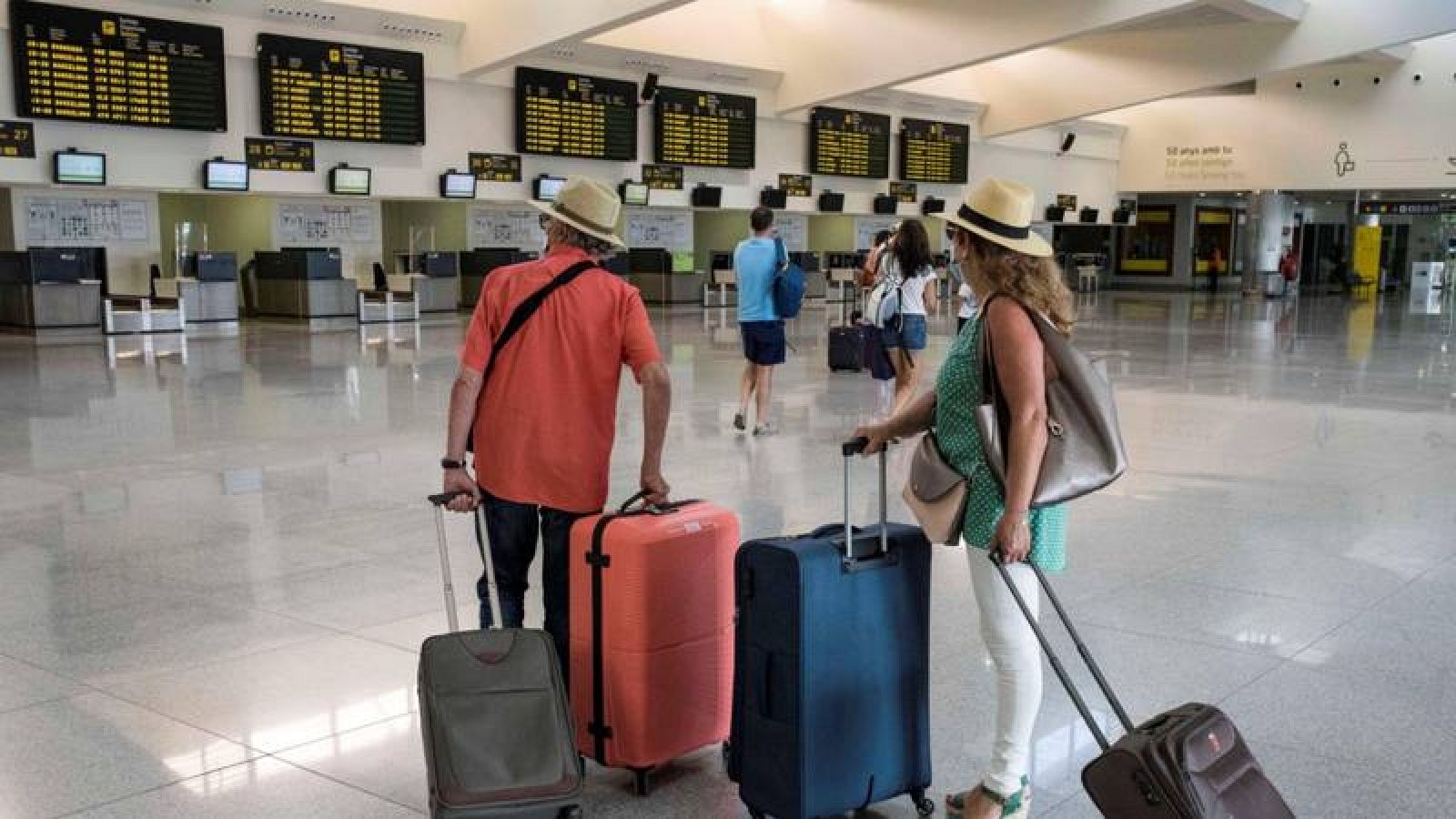 Varios turistas comprueban sus vuelos en el aeropuerto de Mahón, en Menorca