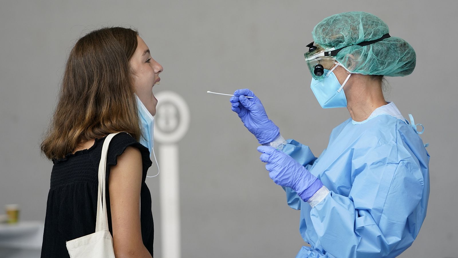 Una trabajadora sanitaria obtiene una muestra de una mujer para someterla a una prueba PCR.
