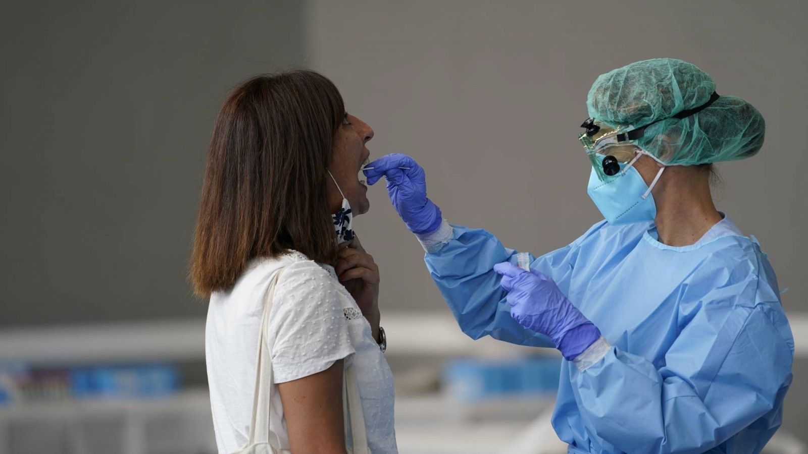 Una trabajadora sanitaria obtiene una muestra de una mujer para someterla a una prueba PCR