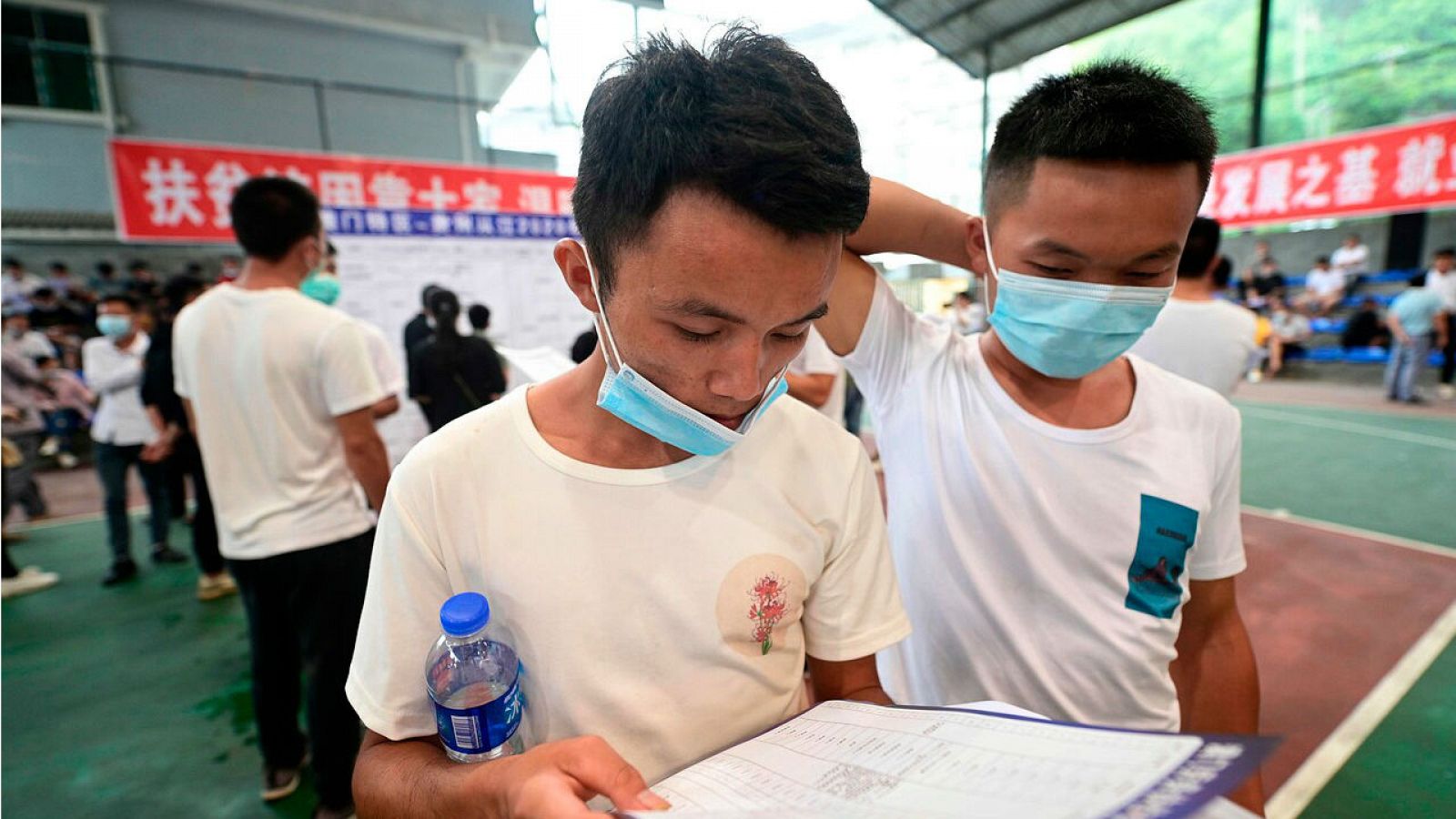 Personas llenando formularios en una feria de empleo en Congjiang, en la provincia de Guizhou, suroeste de China.