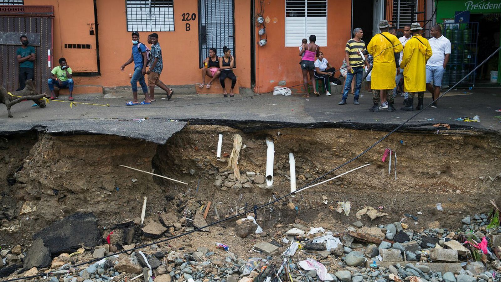 Militares controlan que residentes no se acerquen a la orilla de una calle destrozada debido a las intensas lluvias causadas por la tormenta Laura en Santo Domingo (República Dominicana).