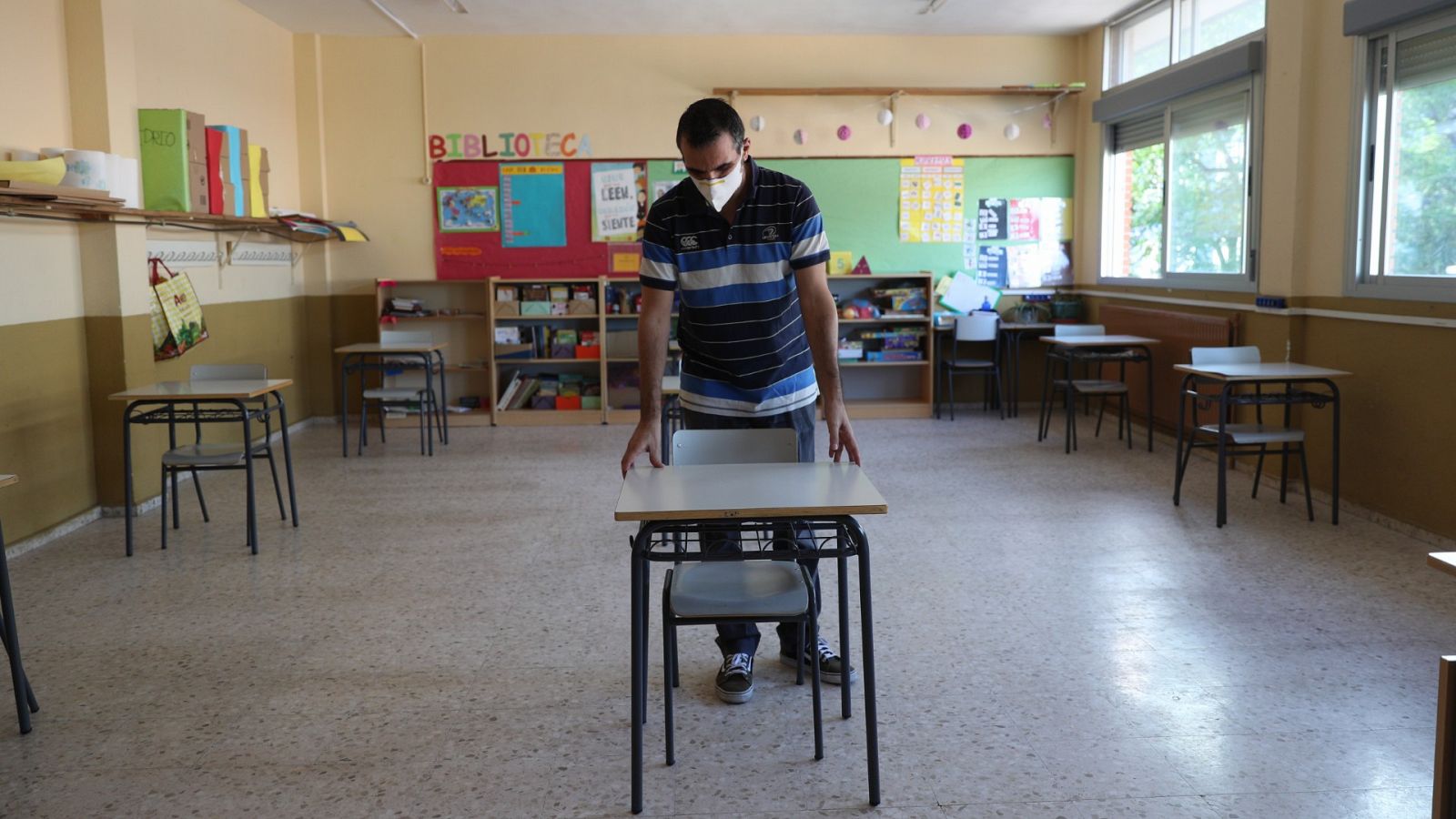 Un profesor coloca las mesas para mantener la distancia de seguridad en un colegio de Torrejón de Ardoz