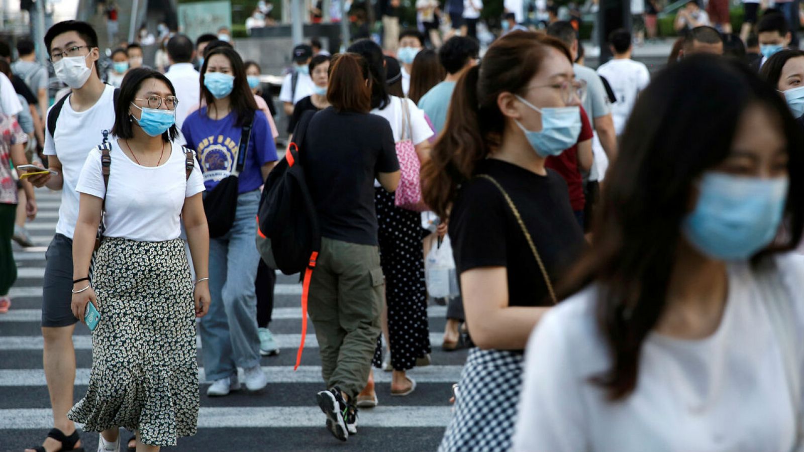 Personas con mascarillas cruzan una calle en un área comercial en Beijing, China.