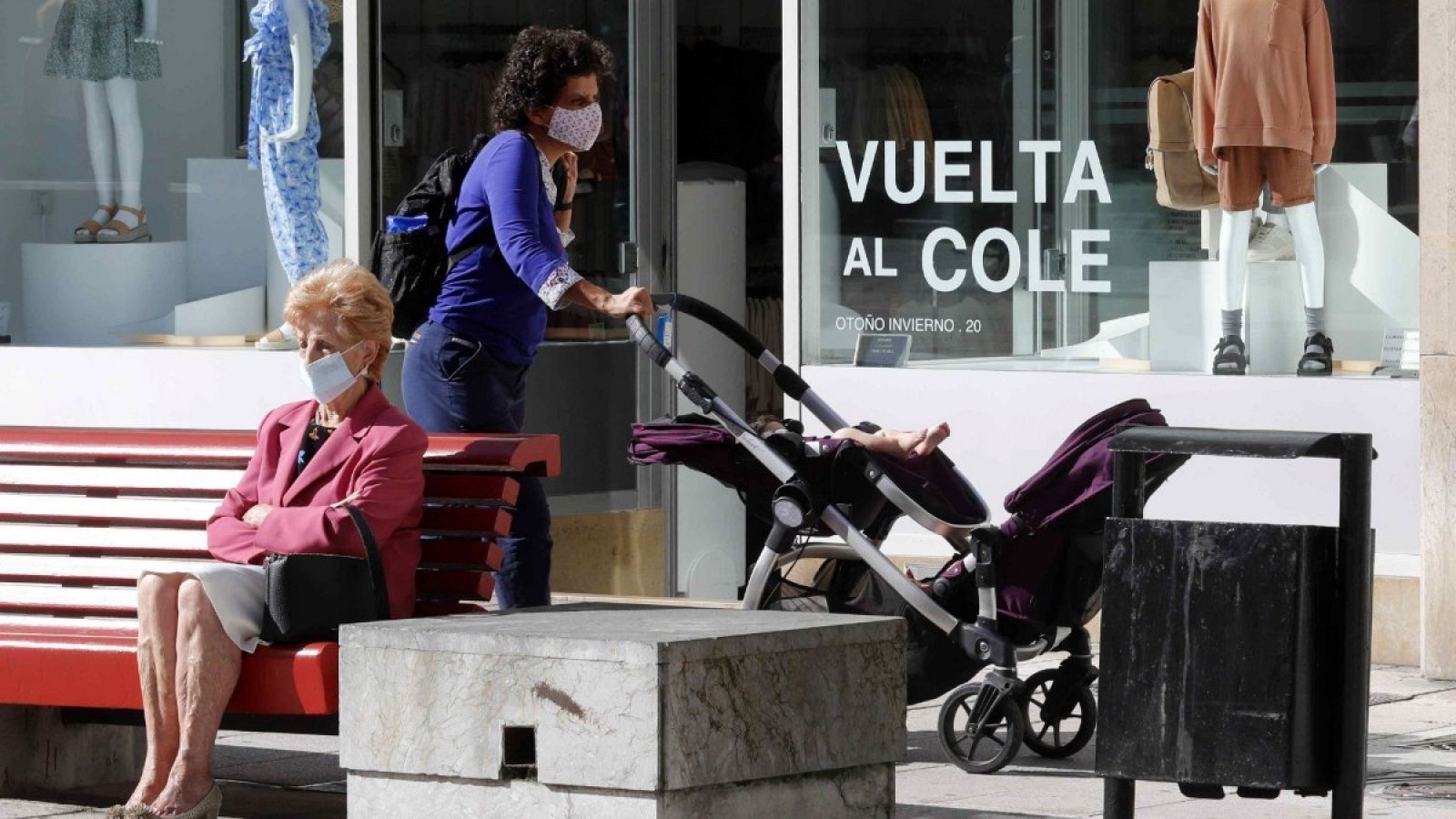 Una mujer camina frente a un escaparate con la campaña de la vuelta al colegio en una calle del centro de Oviedo