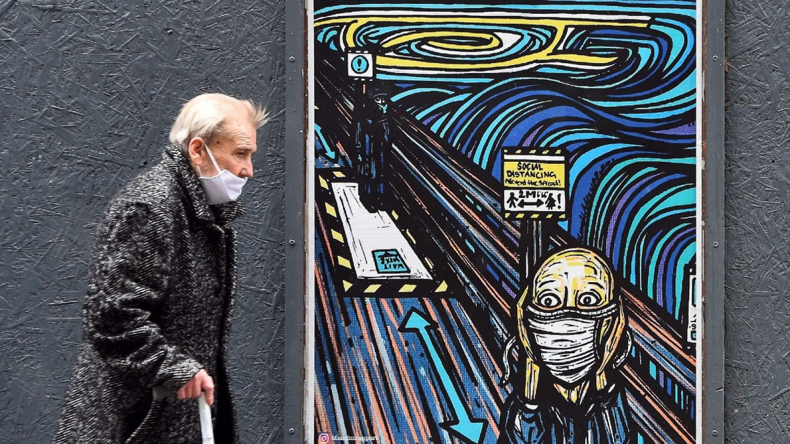 Un peatón con mascarilla pasa por delante de un grafiti que parodia la obra de 'El Grito' de Munch en tiempos de pandemia, en Glasgow.