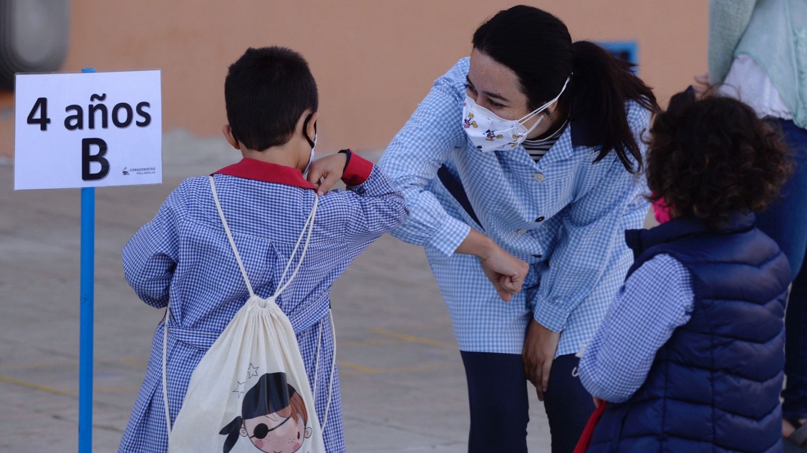 Una profesora y un alumno se saludan en un colegio de Valladolid.
