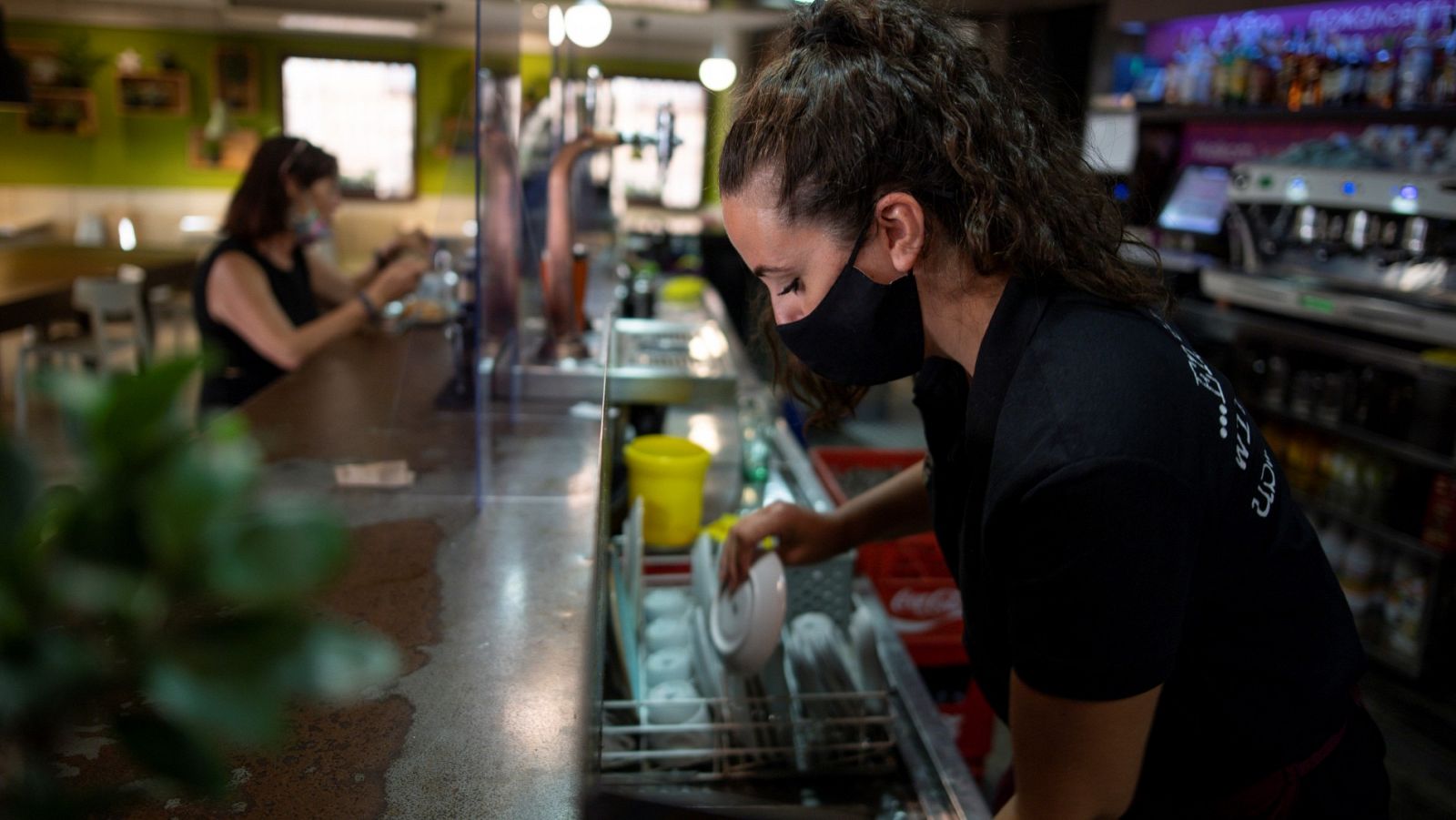 Una camarera seca la vajilla en un bar