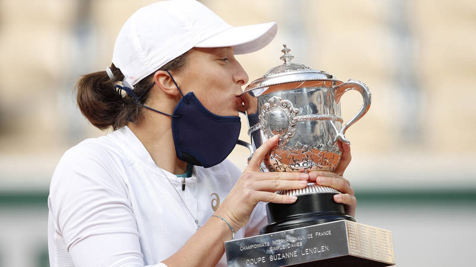 La polaca Iga Swiatek besa con la mascarilla bajada el trofeo de Roland Garros 2020.