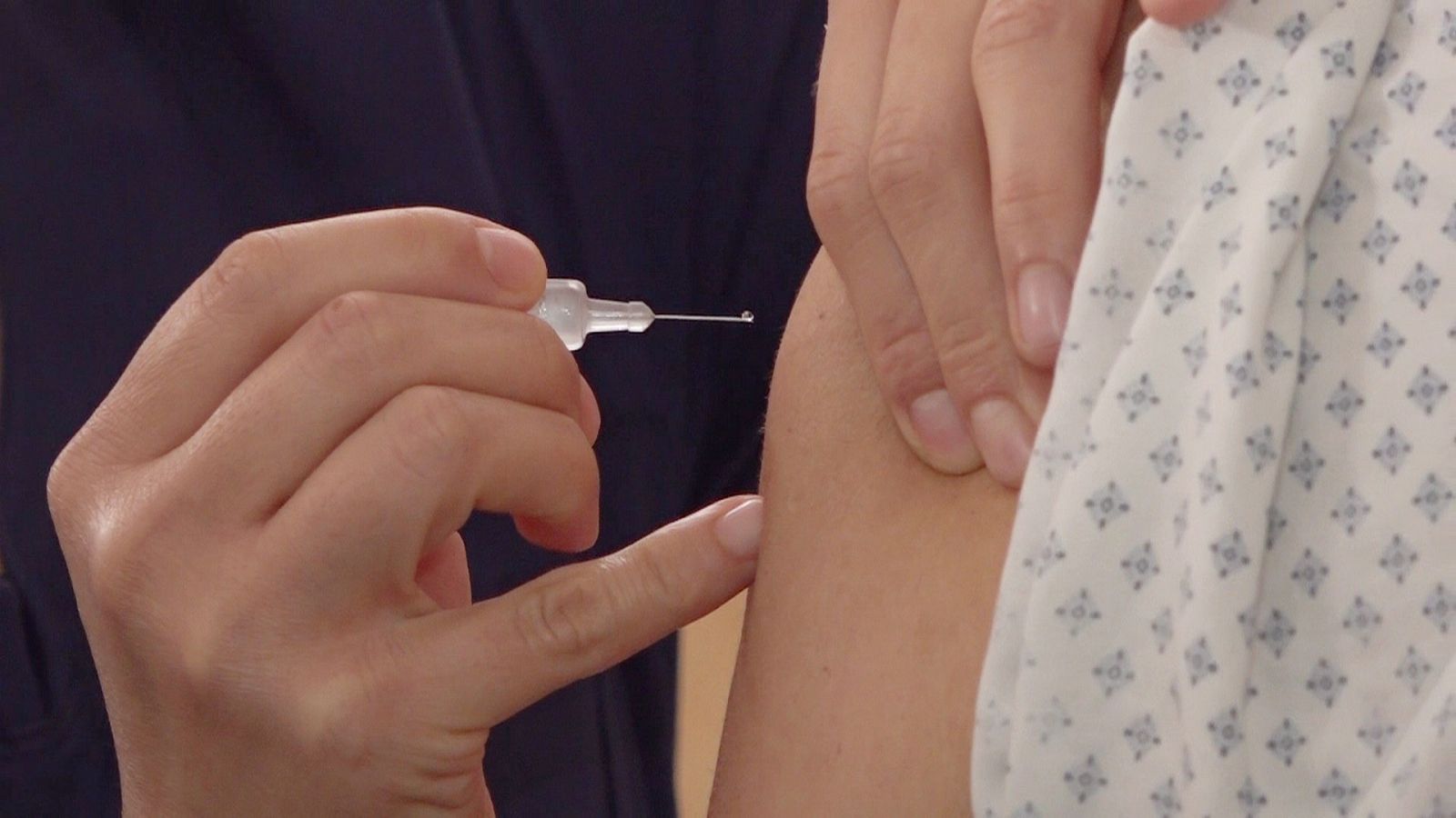 Detalle de una jeringuilla antes de inyectar un medicamento en el brazo.