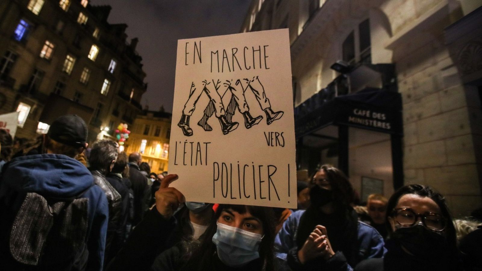 Una manifestante muestra una señal en la que se lee "En marcha hacia un estado policial" en una protesta frente a la Asamblea Nacional, este martes.