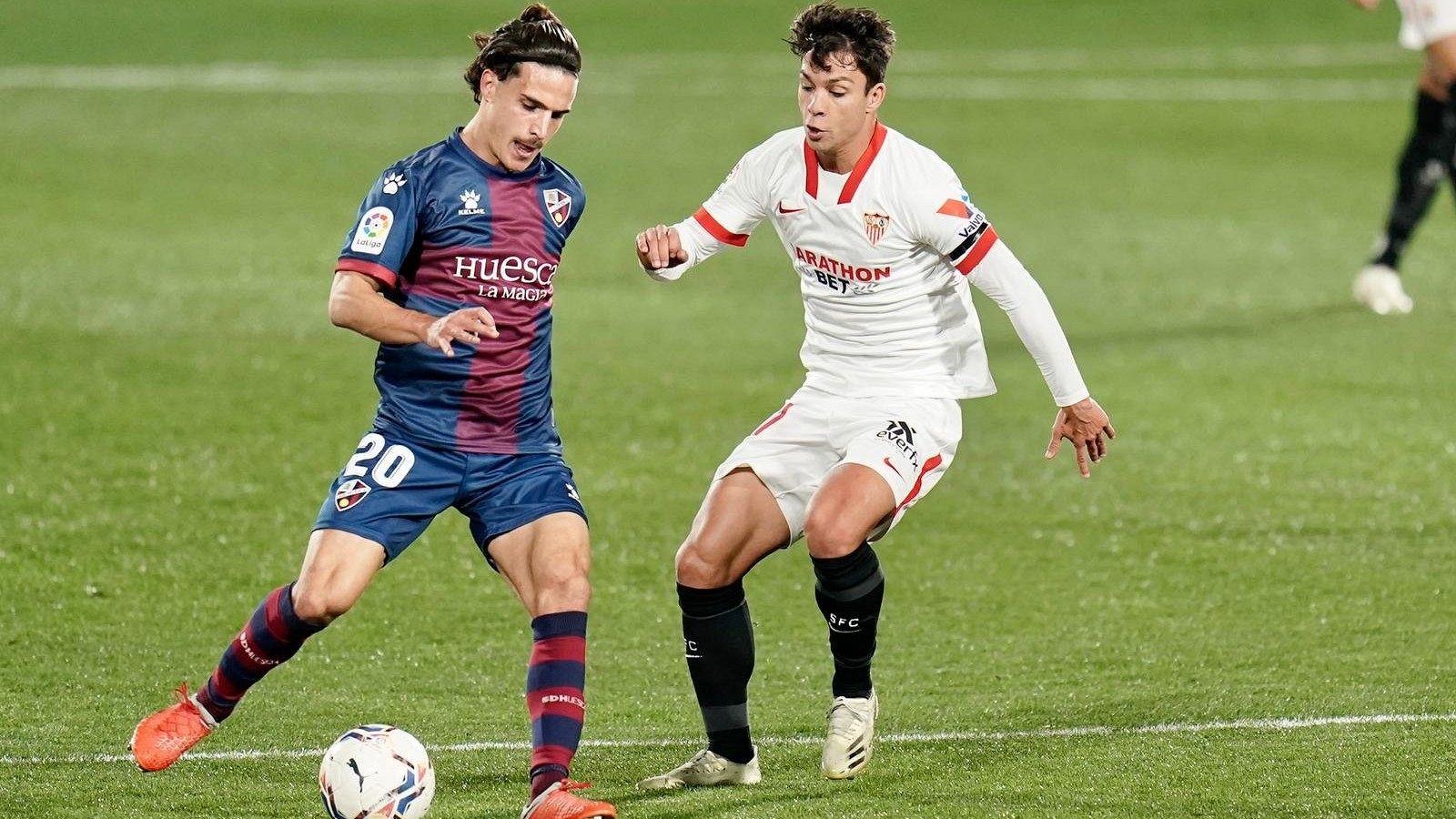 El jugador del Sevilla FC, Óliver Torres, le disputa un balón al futbolista del Huesca. Seoane