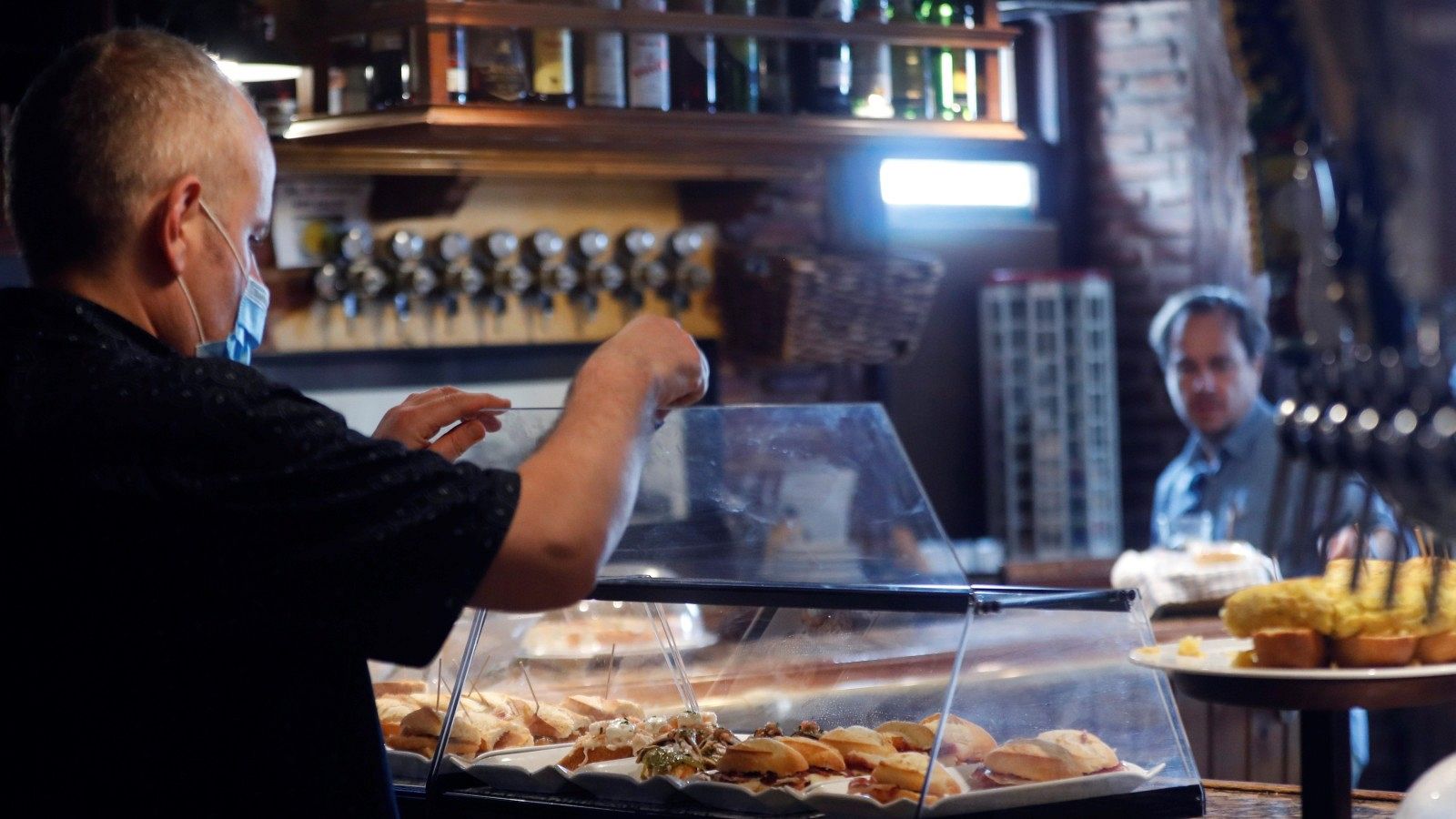 El propietario de un bar de San Sebastián sirve pintxos protegidos por una vitrina este junio, en una imagen de archivo.