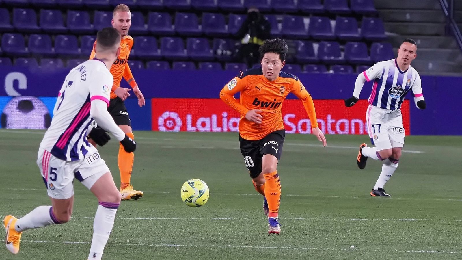 El centrocampista del Valencia Lee Kang-In (c) juega un balón ante Javier Sánchez, del Real Valladolid