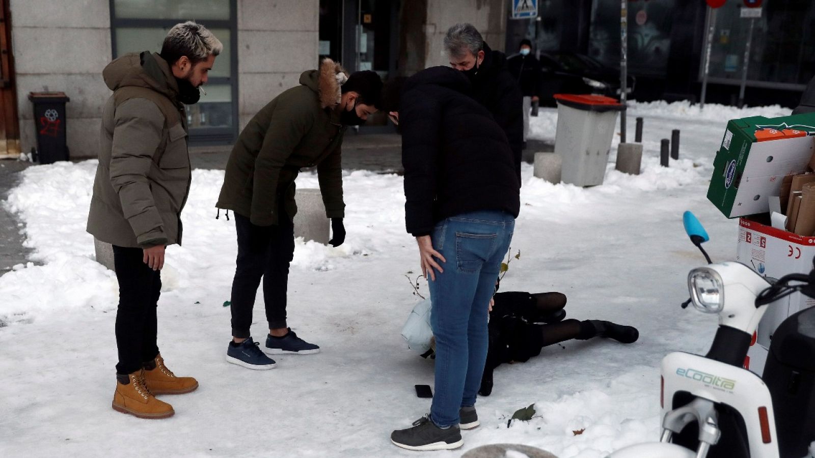 Varias personas asisten a una persona que ha sufrido una caída por el hielo sobre la calzada en Madrid, este miércoles.