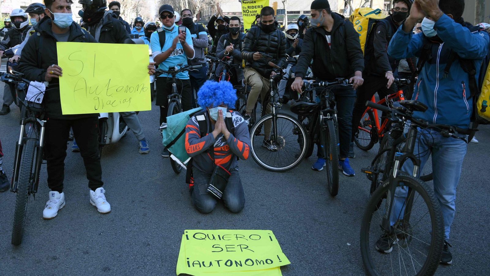 Un repartidor de rodillas muestra un cártel donde se lee "quiero ser autónomo"