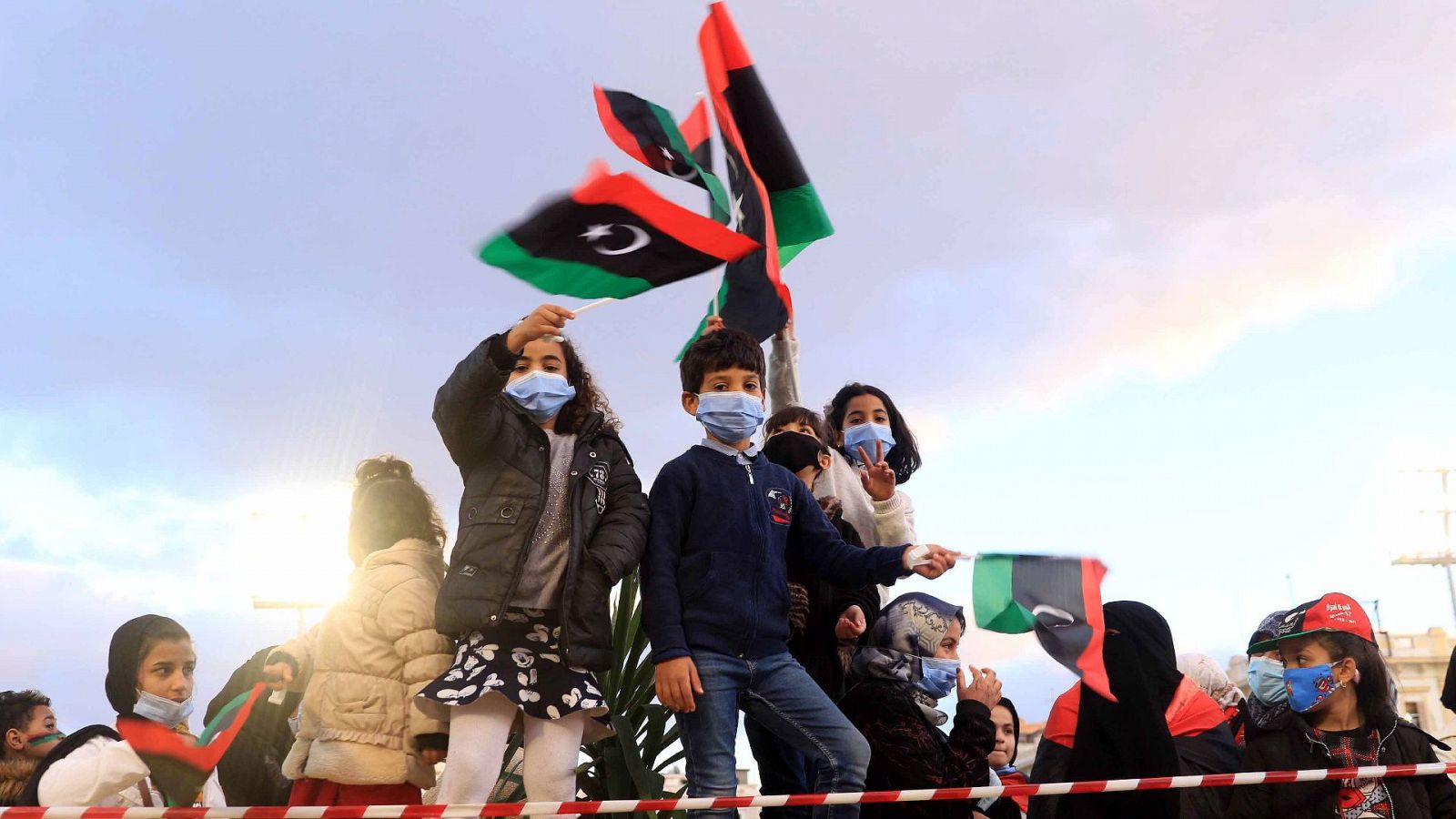 Varios niños sostienen banderas libias en Trípoli un día antes del décimo aniversario del levantamiento contra Gadafi