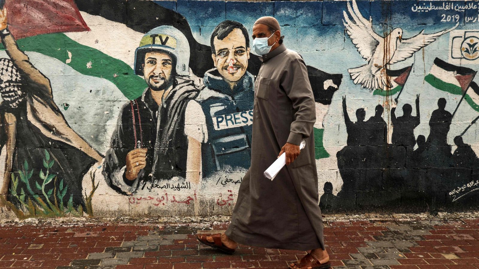 Un palestino pasa junto a un mural de periodistas asesinados en el 2014 entre Hamas e Israel en la ciudad de Gaza
