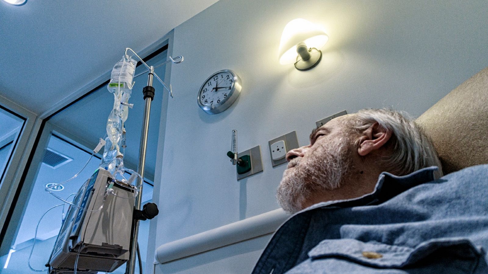 Un paciente de cáncer mira la hora en un reloj mientras recibe su tratamiento.