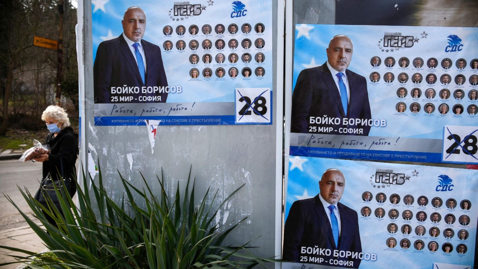 Una mujer pasando al lado de varios carteles electorales con la imagen del primer ministro búlgaro y candidato del GERB, Boiko Borisov.